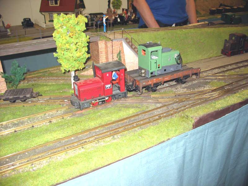 Tren de vía métrica llevando una locomotora de vía estrecha en esa misma maqueta